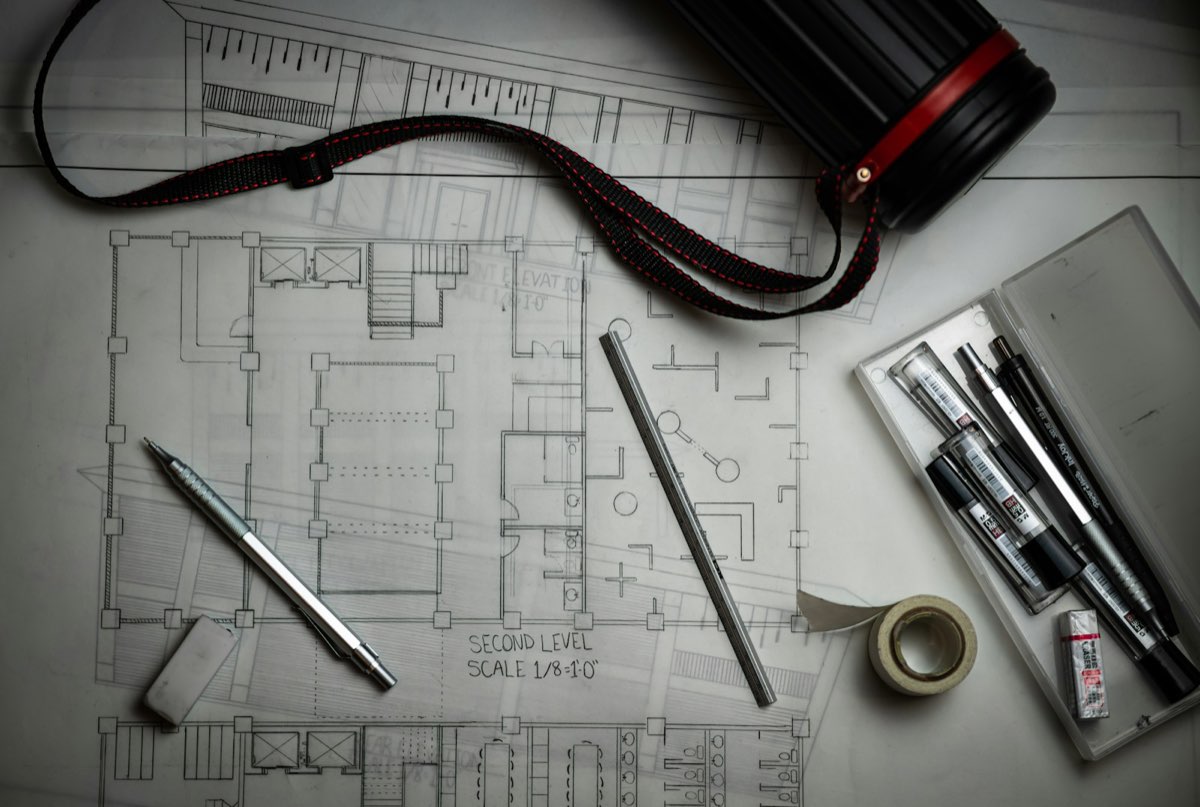 Plantas e instrumentos de desenho sobre a mesa: o projeto sendo desenhado antes de ser construído